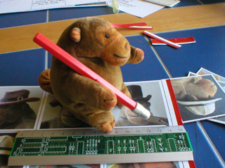 Mr Monkey cutting out a sheet of cards with a craft knife