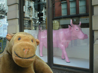 Mr Monkey in front of a piggy bank cow in an office window