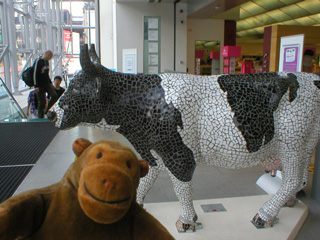Mr Monkey in front of a cow covered in black and white mosaic tiles