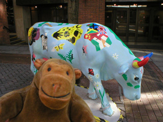 Mr Monkey in front pale bue cow decorated with flags and images of nature