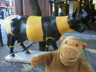 Mr Monkey in front of a cow striped like a bee