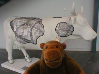 Mr Monkey with a white cow with patches of A-Z style maps of Manchester