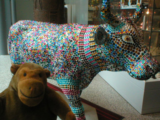 Mr Monkey in front of a cow covered in rows of acrylic gems