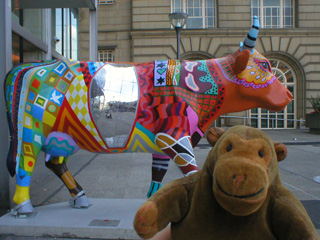Mr Monkey looking at the other side of a brightly patterned cow