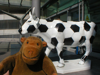 Mr Monkey in front of a cow decorated as a football