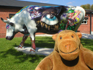 Mr Monkey in front of a cow with a big eye on its side