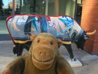 Mr Monkey in front of a cow with pictures of peoples feet