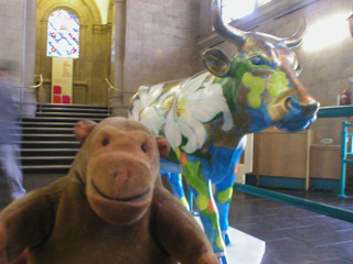 Mr Monkey in front of a cow covered in painted lilies and gold