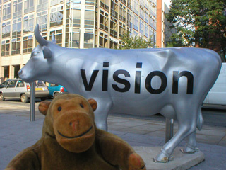 Mr Monkey in front of a cow silver cow with VISION written on it