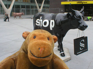 Mr Monkey with a sleek black cow, carrying a carrier bag, with SHOP written on its side