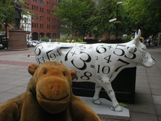 Mr Monkey in front of a cow covered in numbers