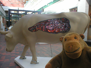 Mr Monkey looking at a cow with a stained glass panel in its side
