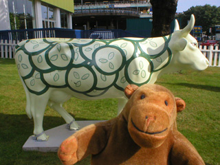 Mr Monkey in front of a cow covered in stylised cucumber slices