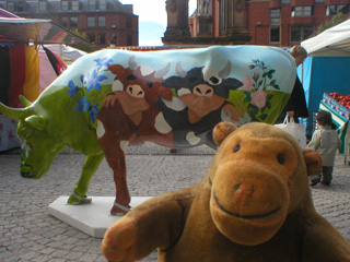 Mr Monkey in front of a cow decorated with two friends dressed as cows in a field