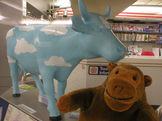 Mr Monkey examining a sky blue cow covered in felt clouds