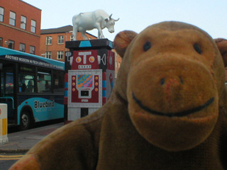 Mr Monkey in front of a white cow on a decorated pillar