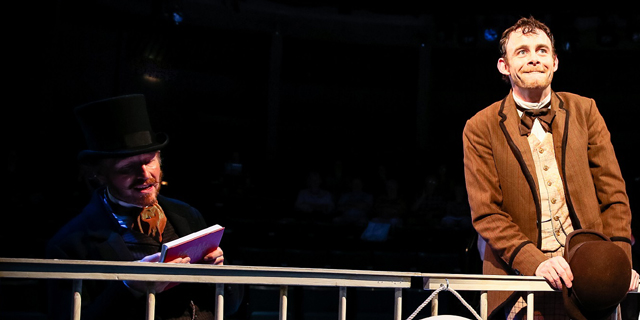 Phileas Fogg (Andrew Pollard) consults his Bradshaws, while Passepartout (Micheal Hugo) looks out to sea (Royal Exchange Theatre production photo)