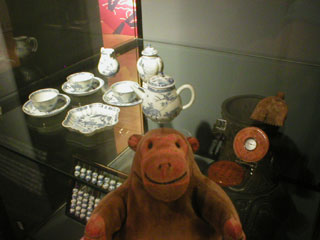 Mr Monkey examining a tea set, a compass and an abacus