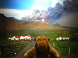 Mr Monkey looking at a photo of a village beneath the volcano by Anna Maria Sigurjondottir
