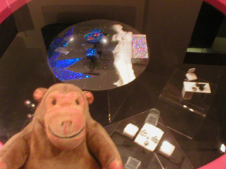 Mr Monkey looking at a set design displayed in the Education Lounge coffee table