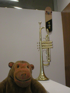 Mr Monkey looking at an unplayable trumpet and an unrideable skateboard