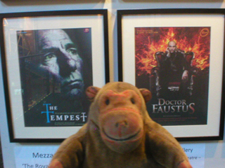 Mr Monkey looking at posters for The Tempest and Dr Faustus