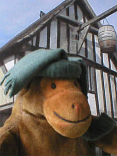 Mr Monkey wearing his chaperon outside a medieval shop