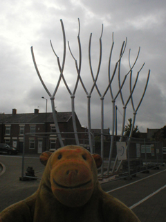 Mr Monkey looking at the sculpture surrounded by fencing