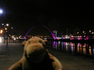 Mr Monkey looking at the Millennium Bridge illuminated as part of Glow