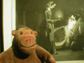 Mr Monkey looking at a print of Miss Nightingale with a candle