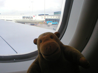 Mr Monkey peering out of the plane window on the tarmac at Amsterdam