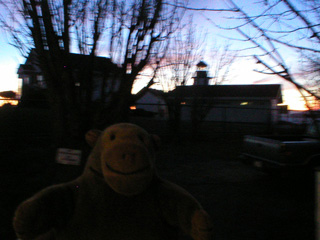 Mr Monkey looking through a fence at the Alki Point lighthouse