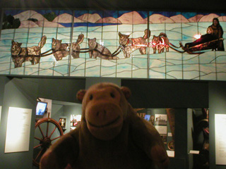 Mr Monkey looking at a stained glass picture of a dog team