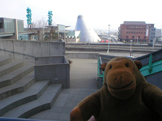 Mr Monkey looking at the Bridge of Glass and the Museum of Glass from the museum archway