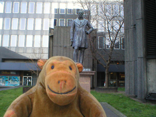 Mr Monkey in front of a statue of Robert Stephenson