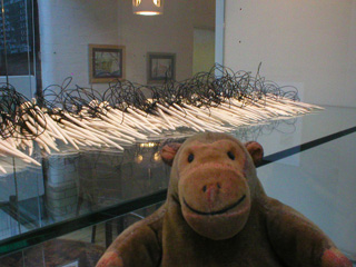 Mr Monkey looking at Flotsam, a row of porcelain pins linked by twine