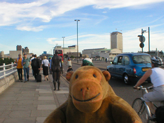 Mr Monkey walking up behind a Gormley figure