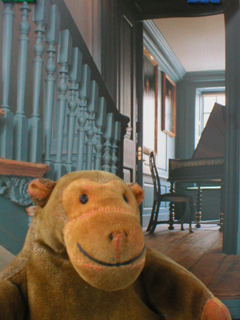 Mr Monkey in front of a photo of the stairwell outside Handel's music room