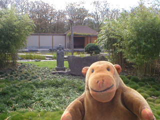 Mr Monkey looking at bamboo, a rock and a statue