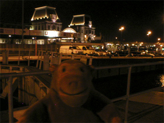 Mr Monkey looking at Ostende station from Visserkaai at night