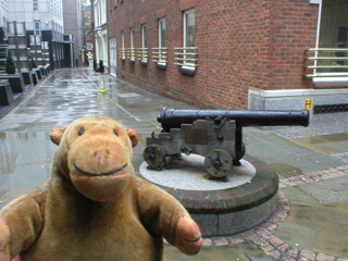 Mr Monkey looking at a naval cannon on a plinth