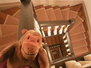 Mr Monkey looking over the bannisters and down into the stairwell