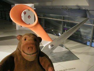 Mr Monkey examining a giant pair of scissors