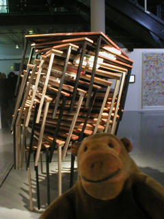 Mr Monkey looking at Andrew Lim's stack of tables and books