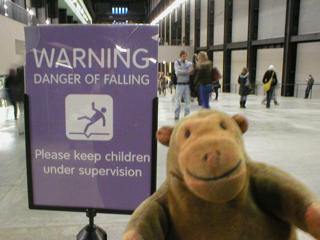 Mr Monkey reading a warning sign in the Turbine Hall