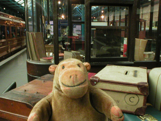 Mr Monkey looking at a ticket booth surrounded by luggage