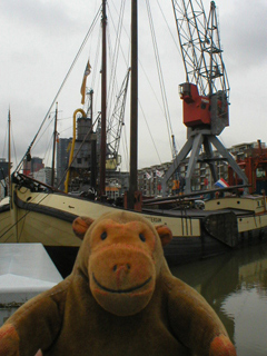 Mr Monkey looking at a barge and crane on the Leuvehaven