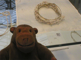 Mr Monkey looking at a metal and porcelain bracelet