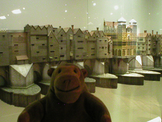 Mr Monkey looking at a model of London Bridge in 1600