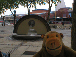 Mr Monkey watching water pouring from a lion's head fountain